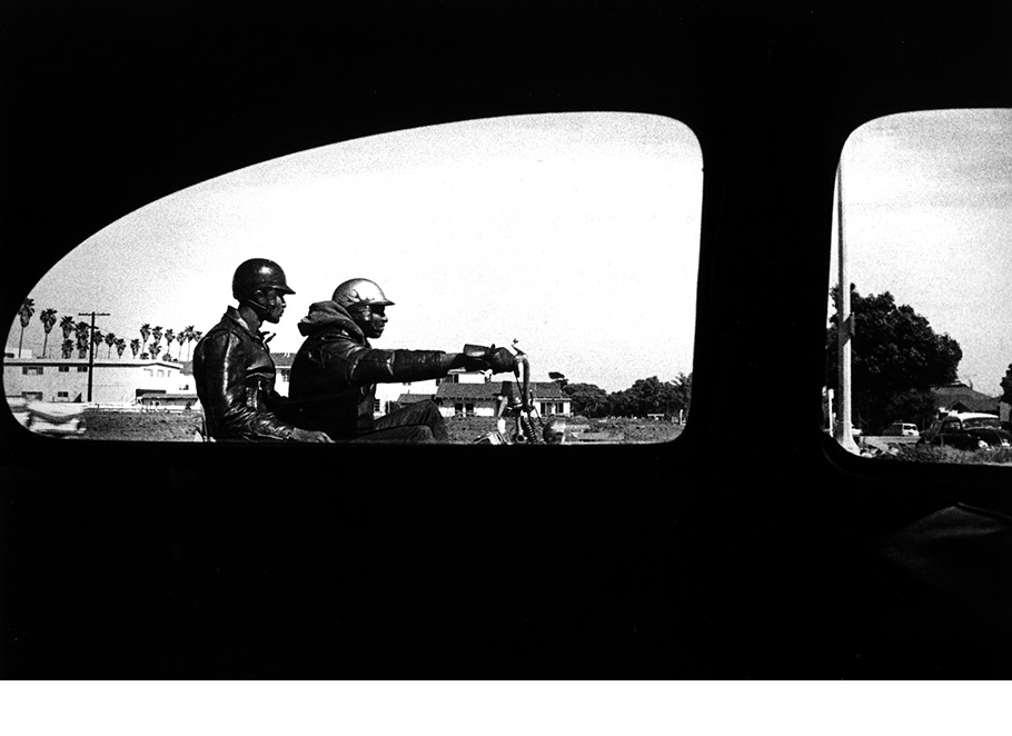 Two men on motorcycle photographed through window - Los Angeles, 1964.