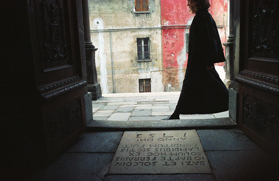 Woman walking past door front - Mergozzo, 2005.