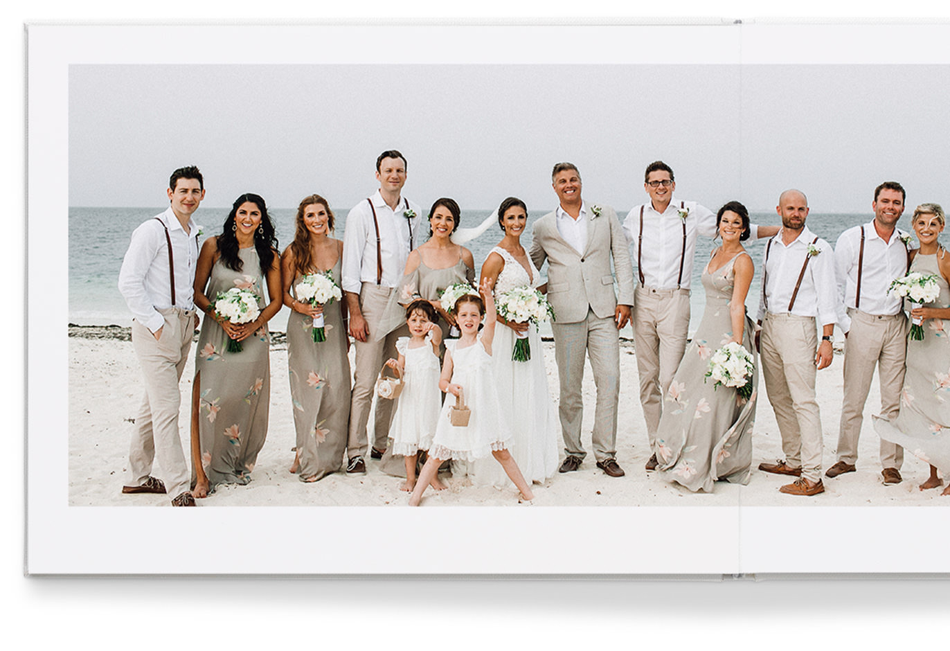 Álbum de fotos premium em formato paisagem com imagem de 6 impressões de uma noiva, noivo e convidados de casamento na praia.