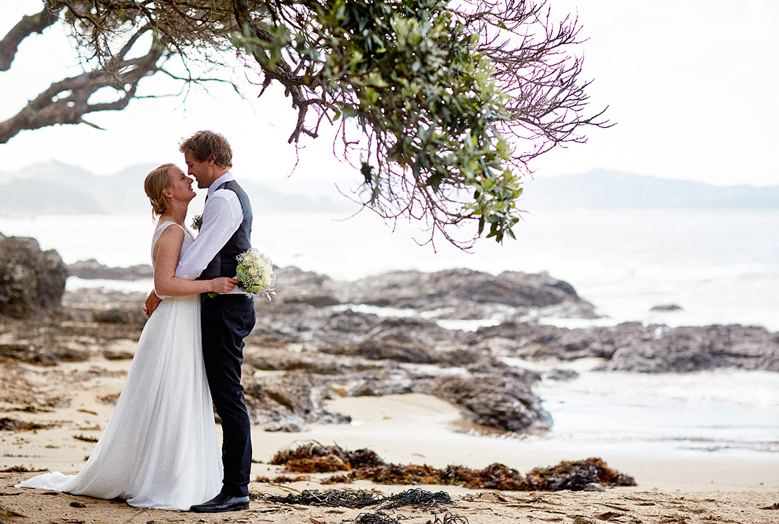 Couple s'embrassant sur la plage le jour de leur mariage.
