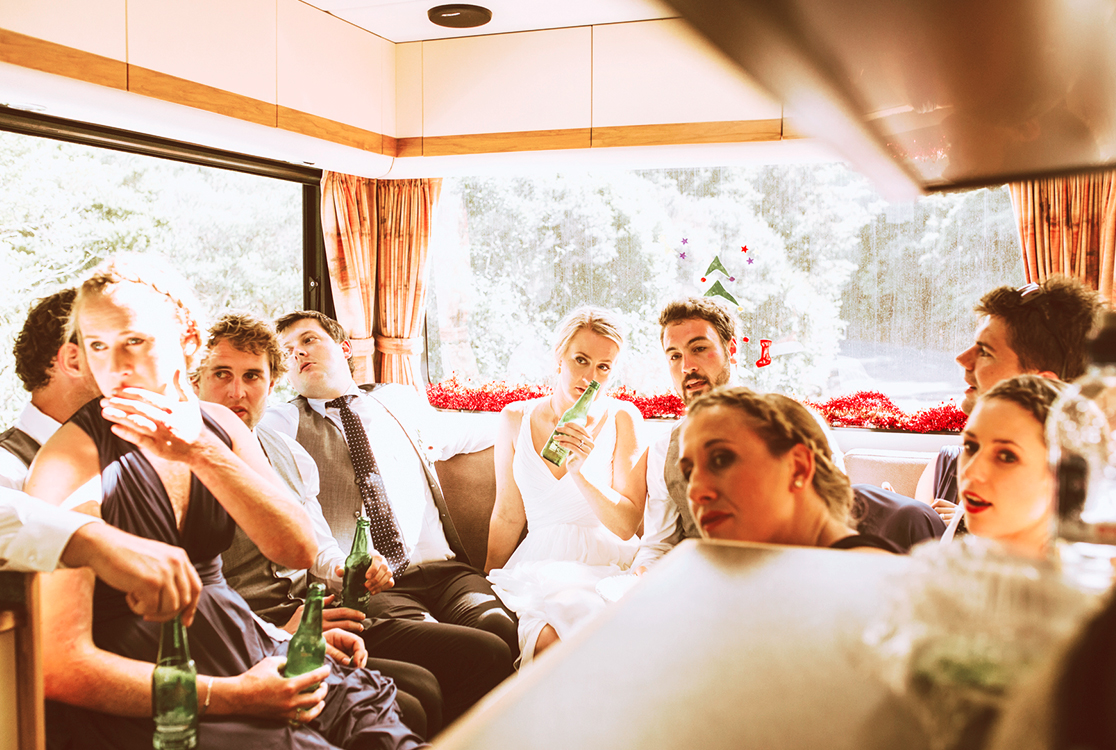 Couple de mariés assis, buvant et riant dans une caravane en mouvement.
