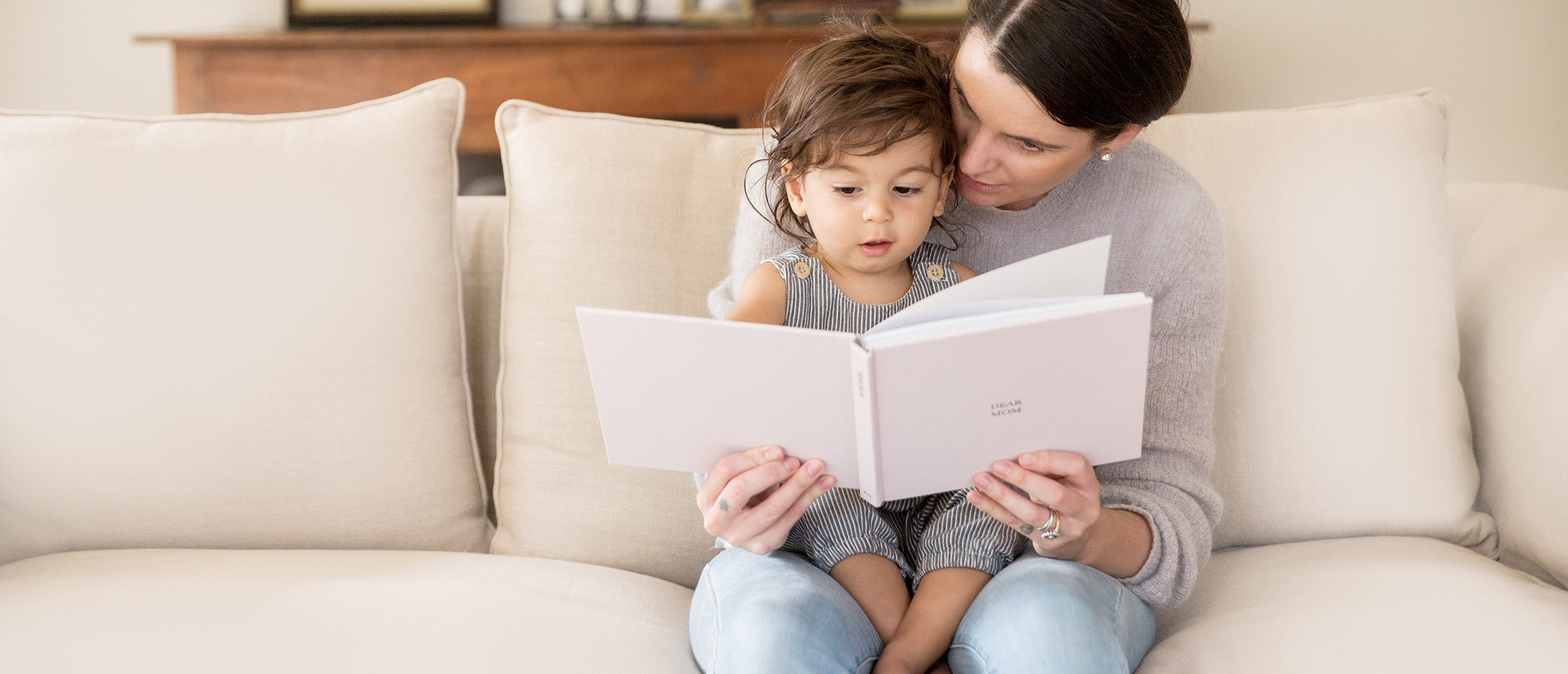 Mother and child looking through MILK Photo Book together on couch