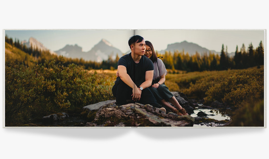 Open photo book with full double page image of a couple in nature.