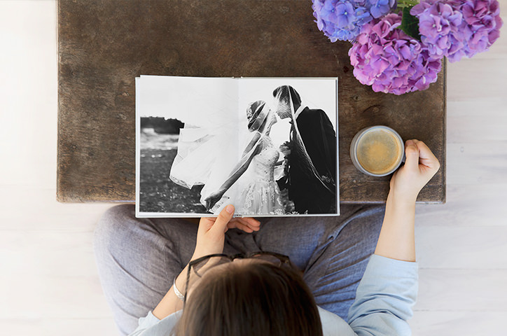 Woman sitting at coffee table with a coffee looking at her wedding album.