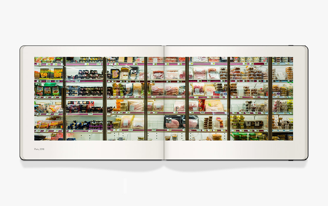 Open Moleskine photo book with double page photo of a supermarket fridge.