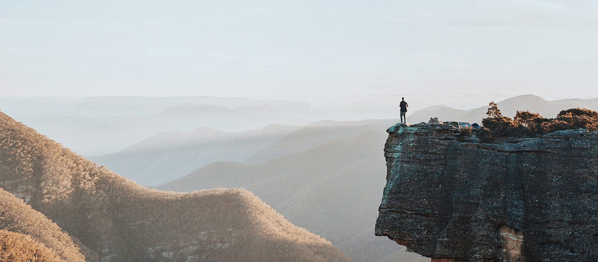 Man on cliff overlooking the hills