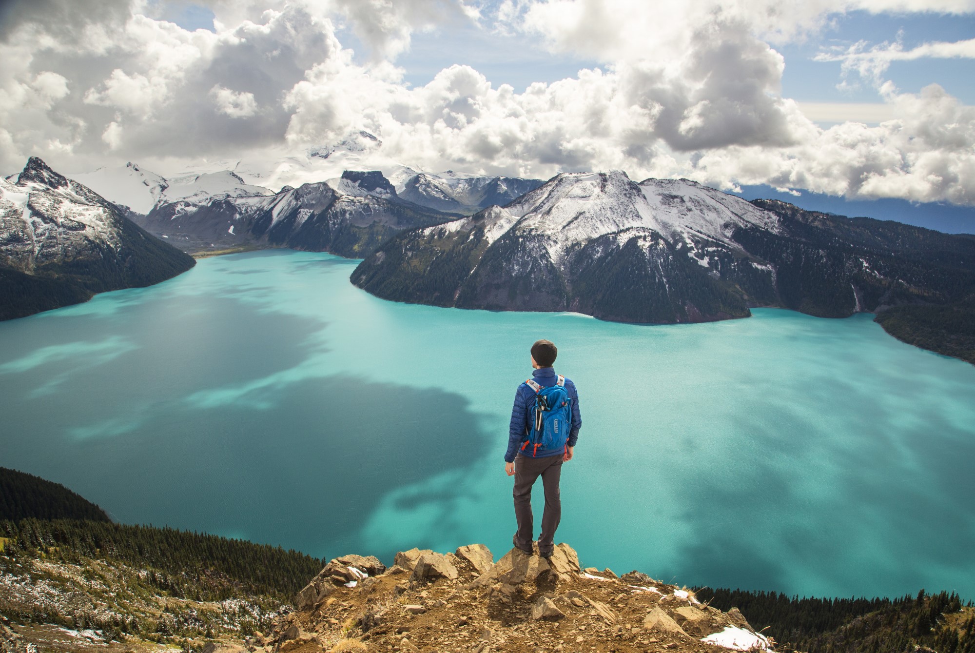 Man overlooking a lake from a hilltop.