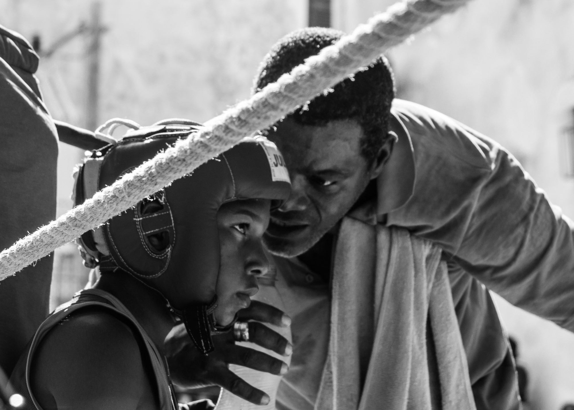 Man speaking to a young boxer at the corner of the ring.