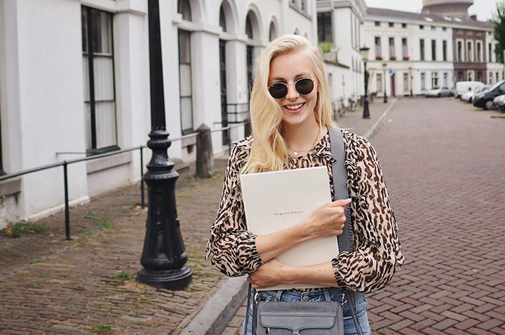 Travel blogger holding photo book on cobbled street