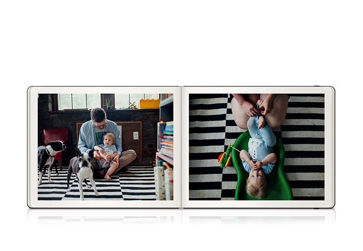 Landscape Moleskine family photo book laying open with two photos of a father, mother, son and two puppies.