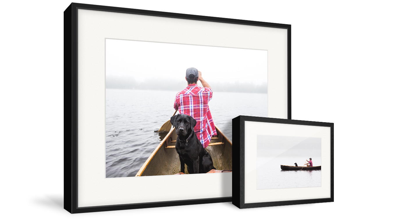 Two gallery frames with images of a man and his dog in a canoe.
