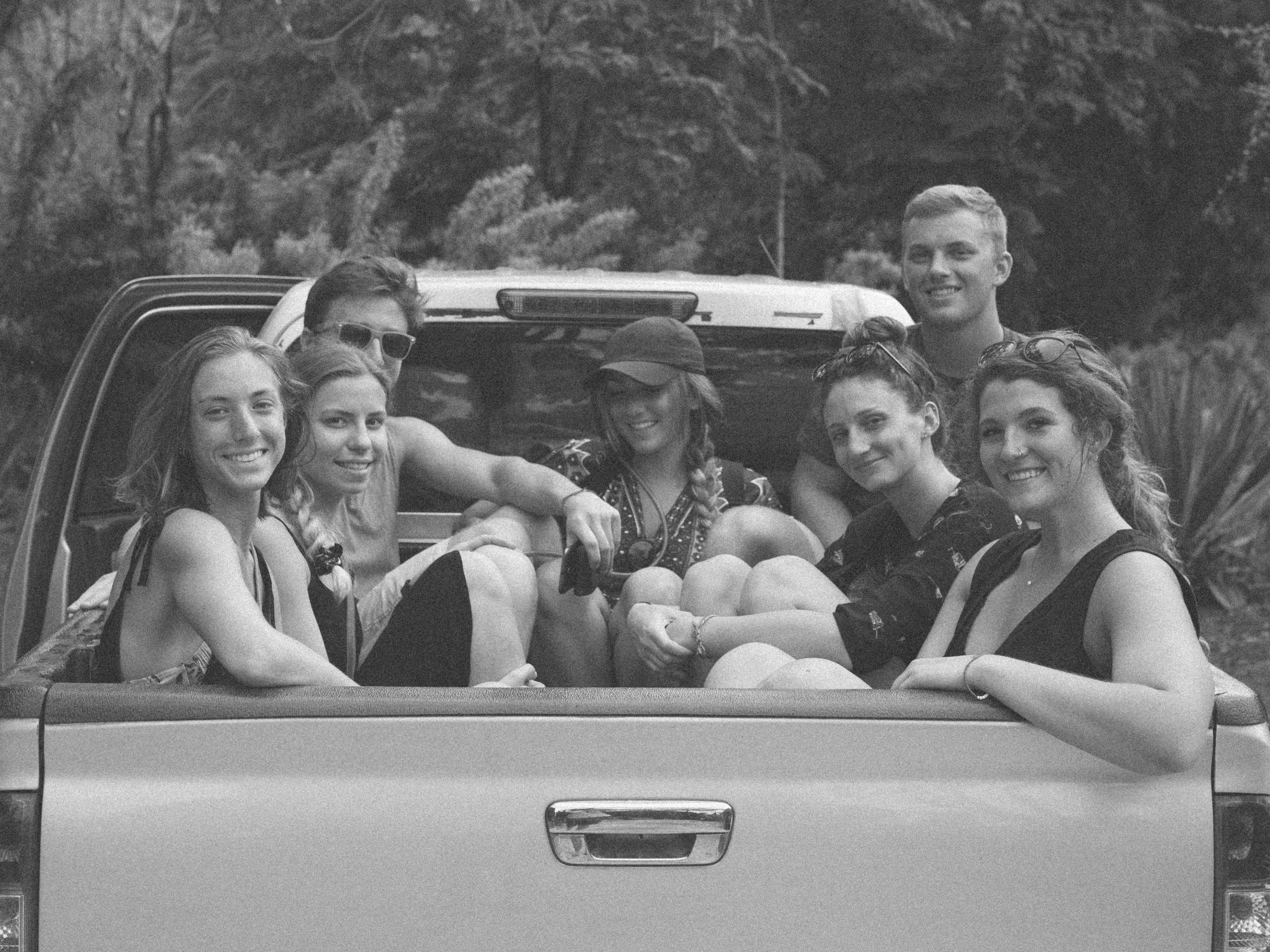 Group of friends smiling in back of ute truck.
