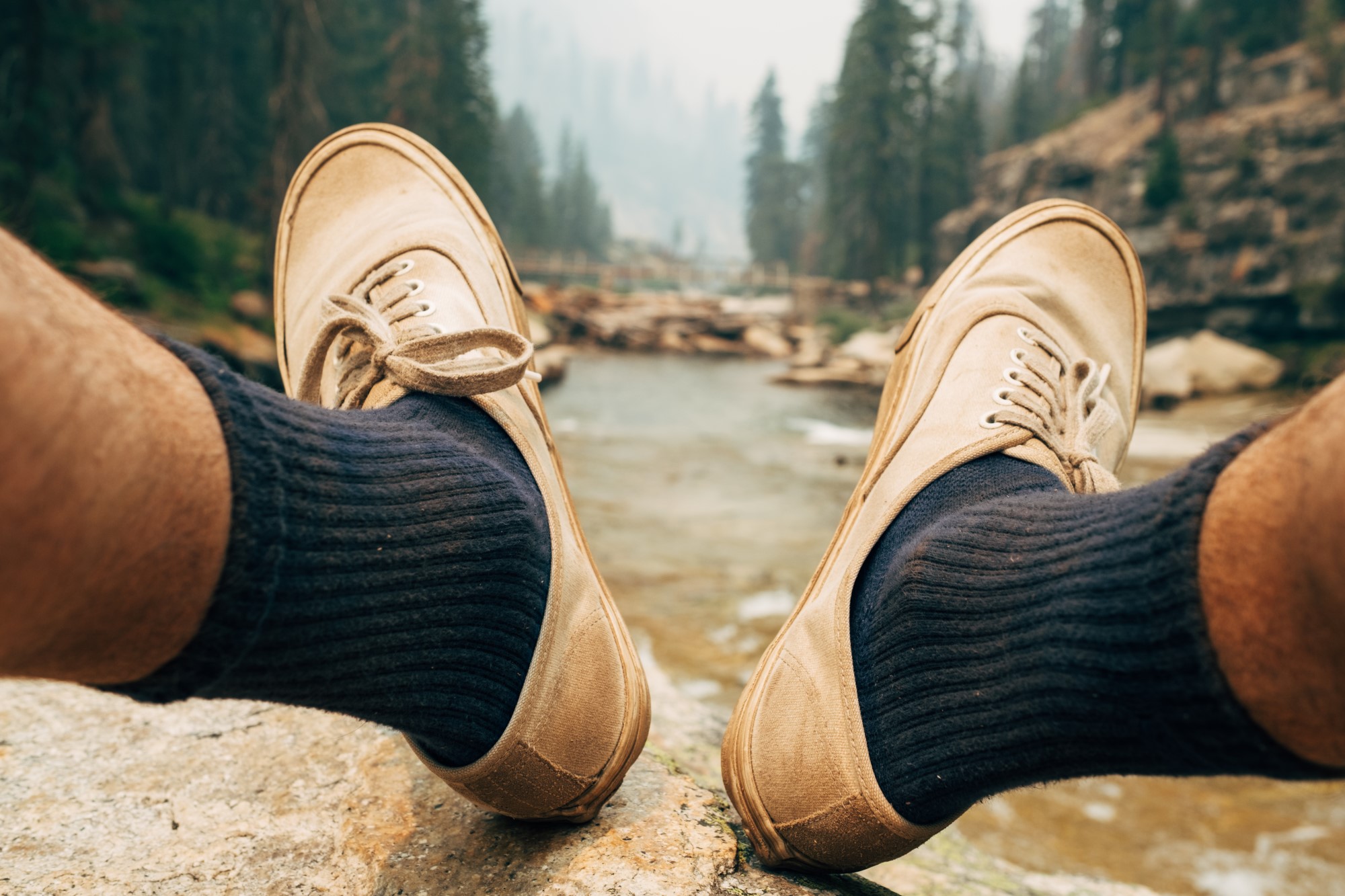 Closeup of man's white shoes and blue socks.