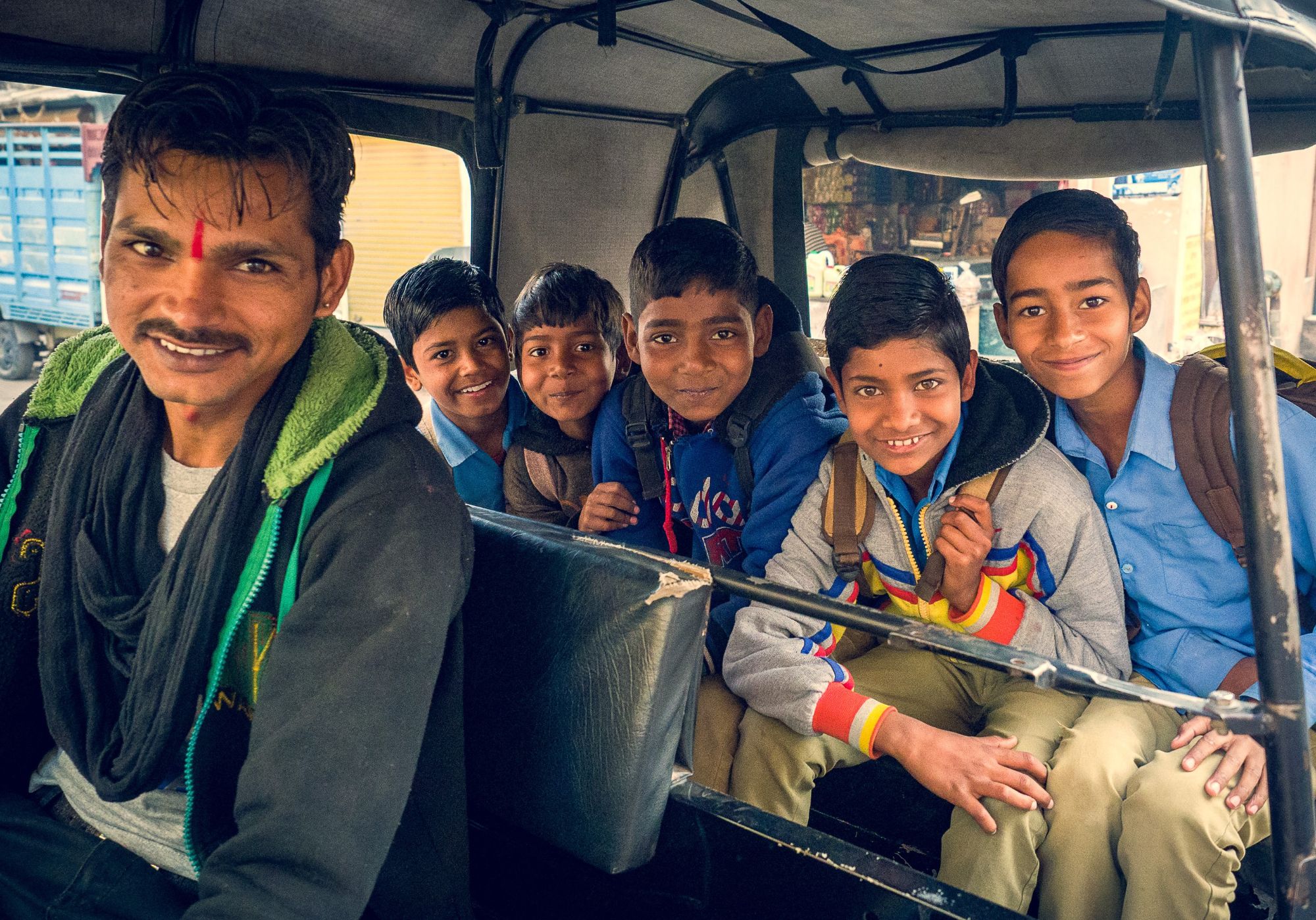 Driver and young kids smiling in transport in India.