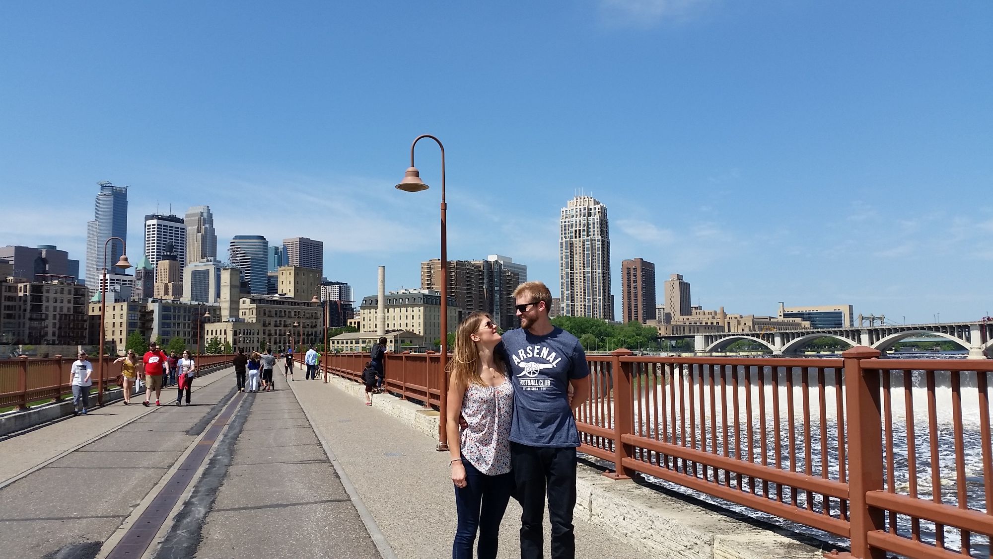 Couple smiling at each other on bridge in city.