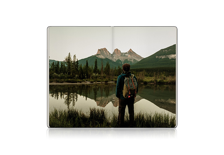 Open photo book showing photo of man looking at mountains and lake ahead