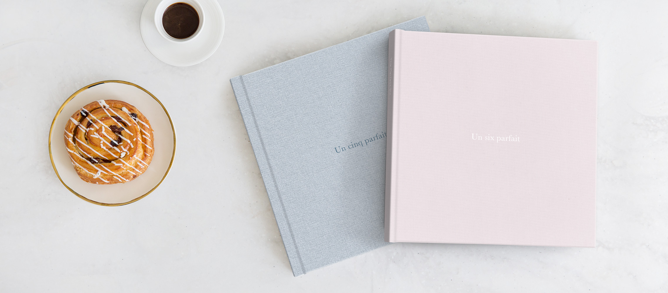 Deux albums de photos d'anniversaire sur une table à côté d'un café et d'un croissant.