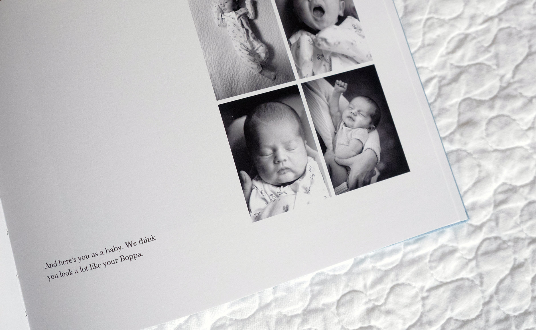 Geöffnetes Baby-Fotobuch auf einem Bett.
