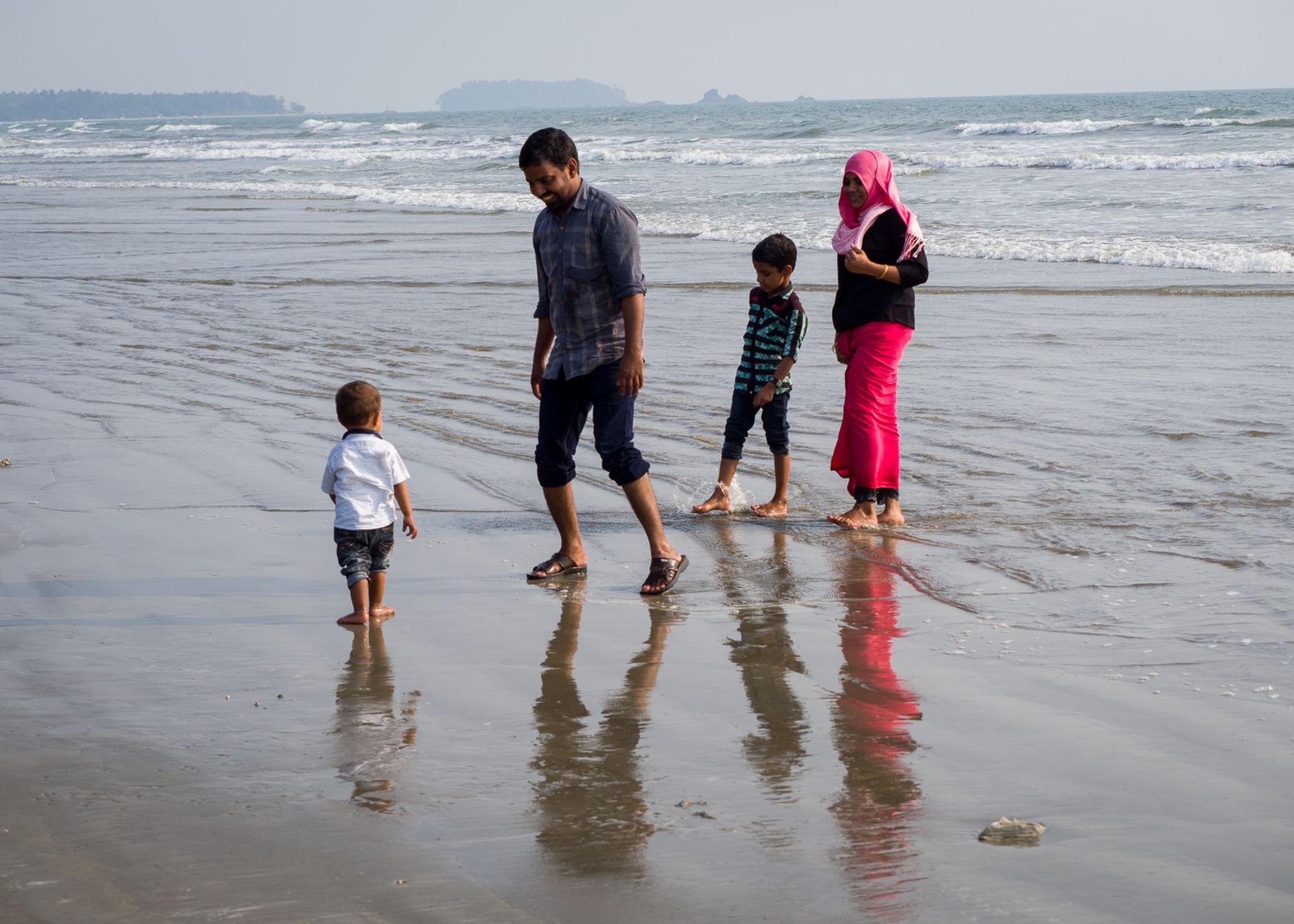 Family at the beach paddling at the shoreline.