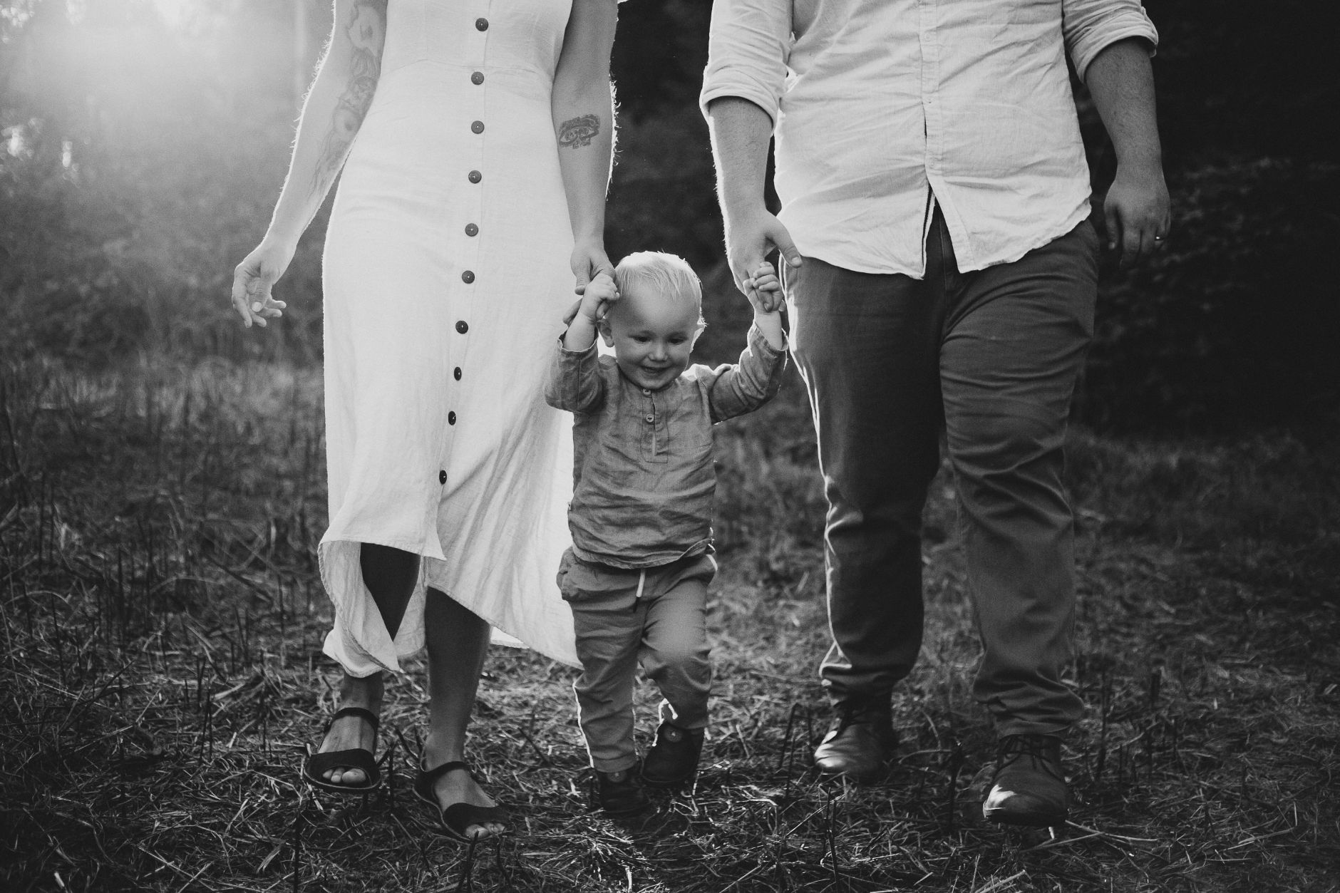 Young child holding hands of mother and father.