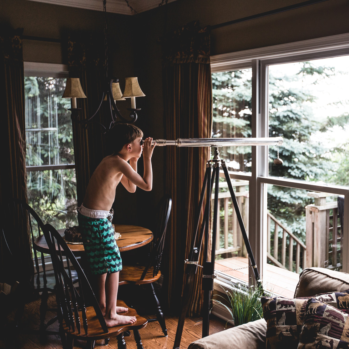 Boy indoors looking through a telescope.
