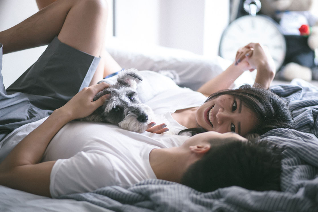 Couple and their dog lying on bed.