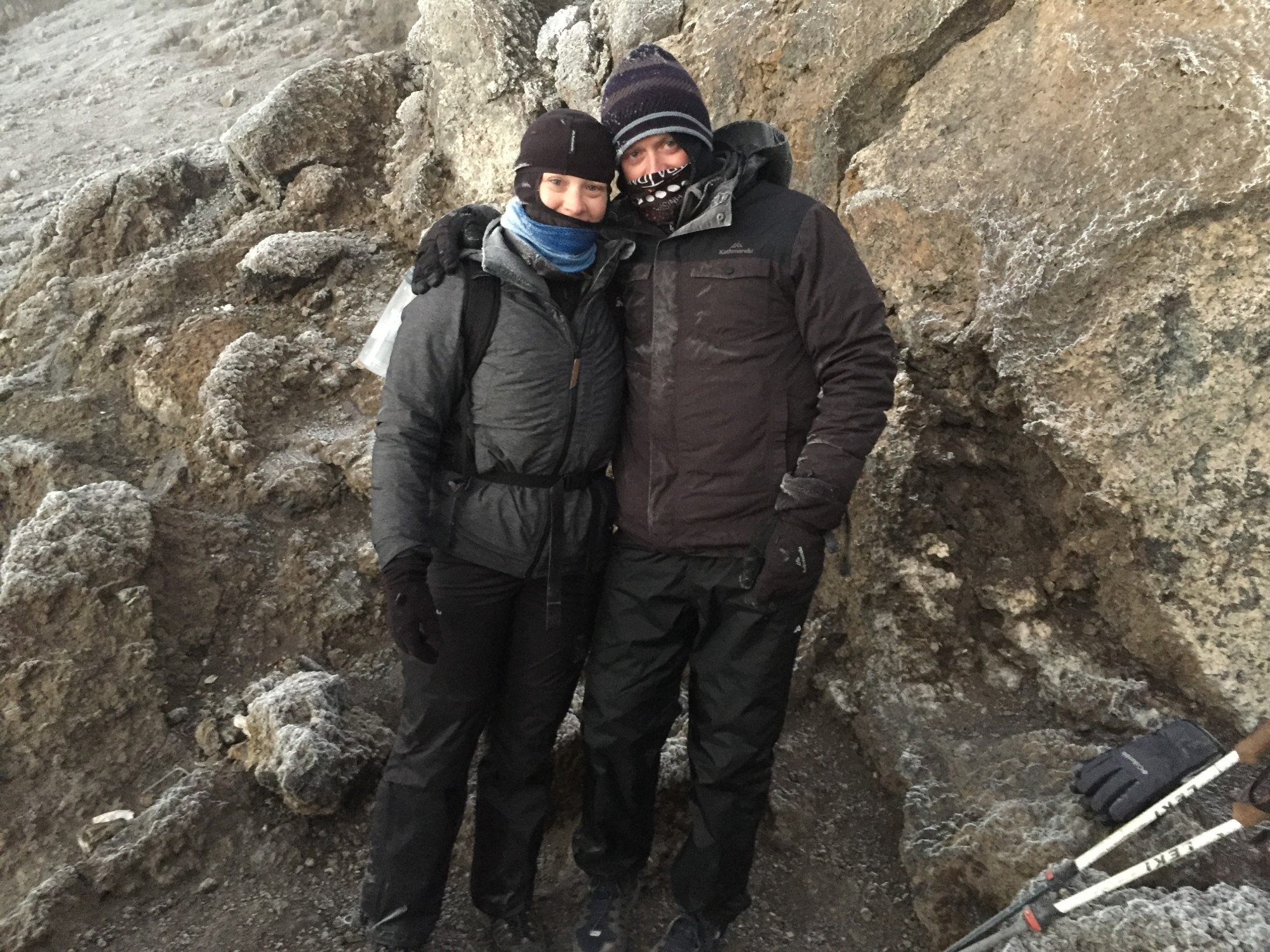 Two people posing for a photo in front of rockface.