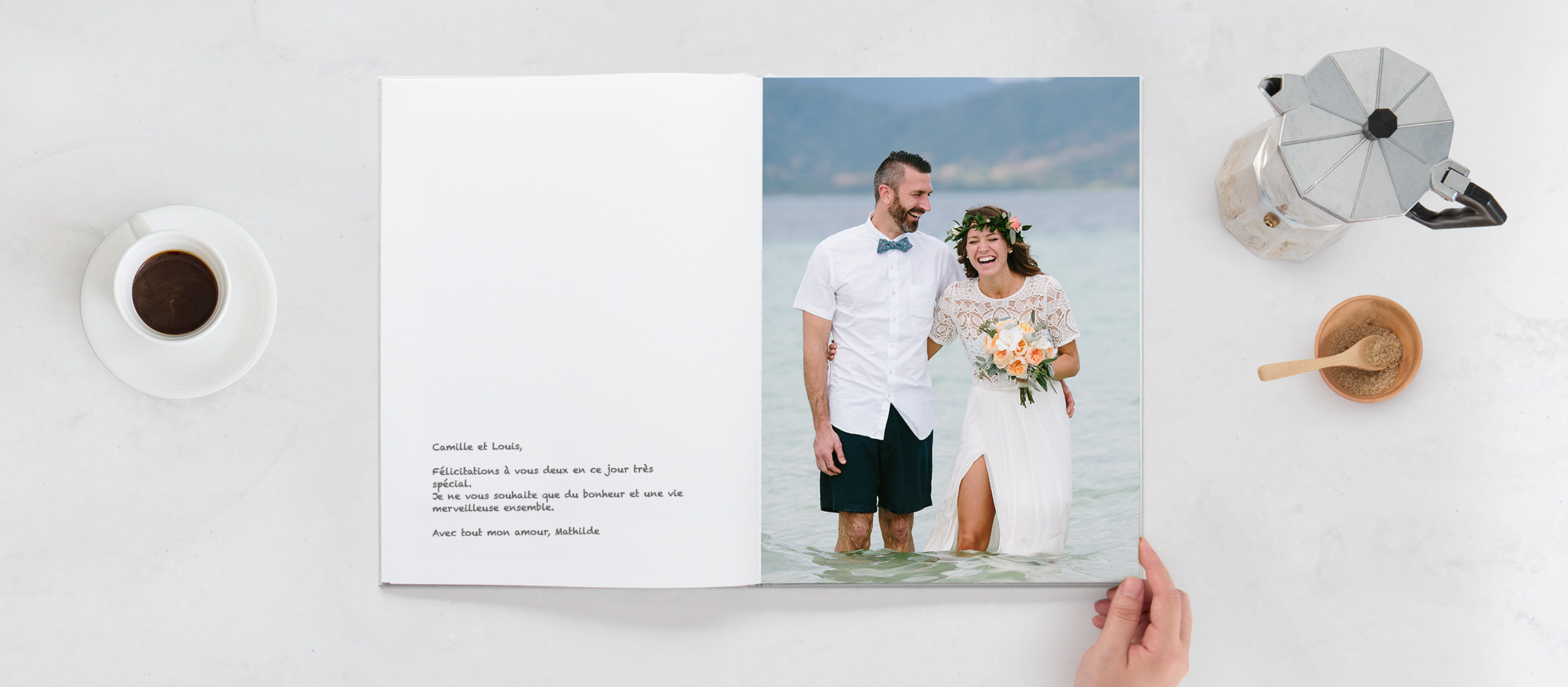 Livre d'or ouvert avec des mariés souriants dans l'eau et une inscription sur la page blanche.