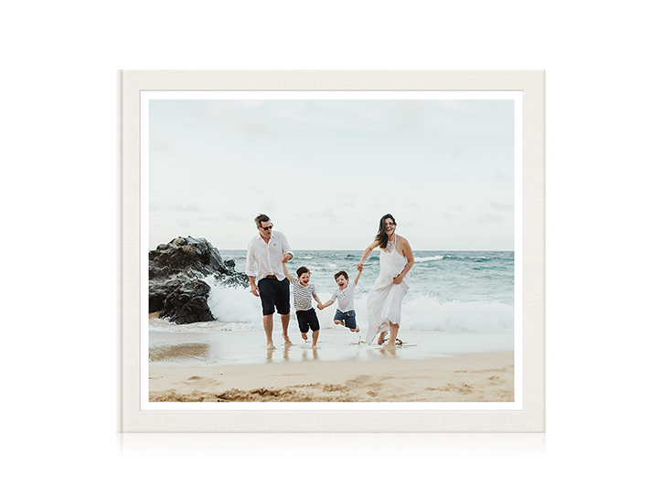 Klassisches Fotobuch mit Cover einer vierköpfigen Familie, die am Strand spielt.