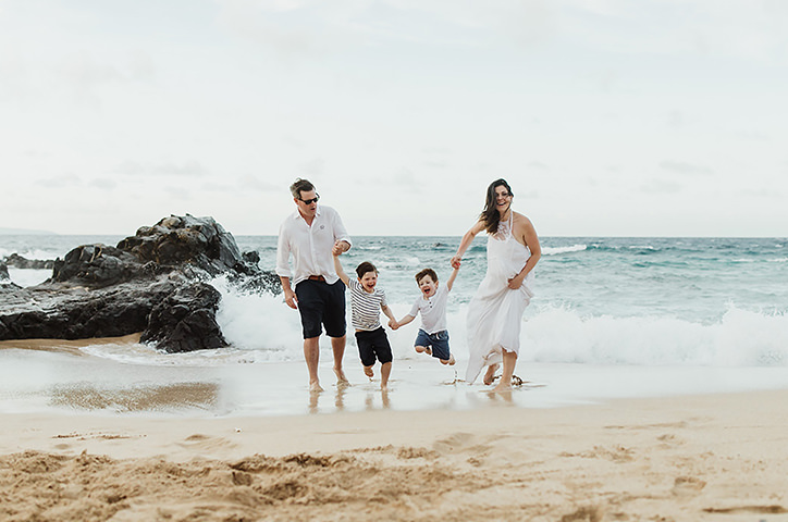 Eine Familie in weißer Kleidung spielt am Meeresufer.