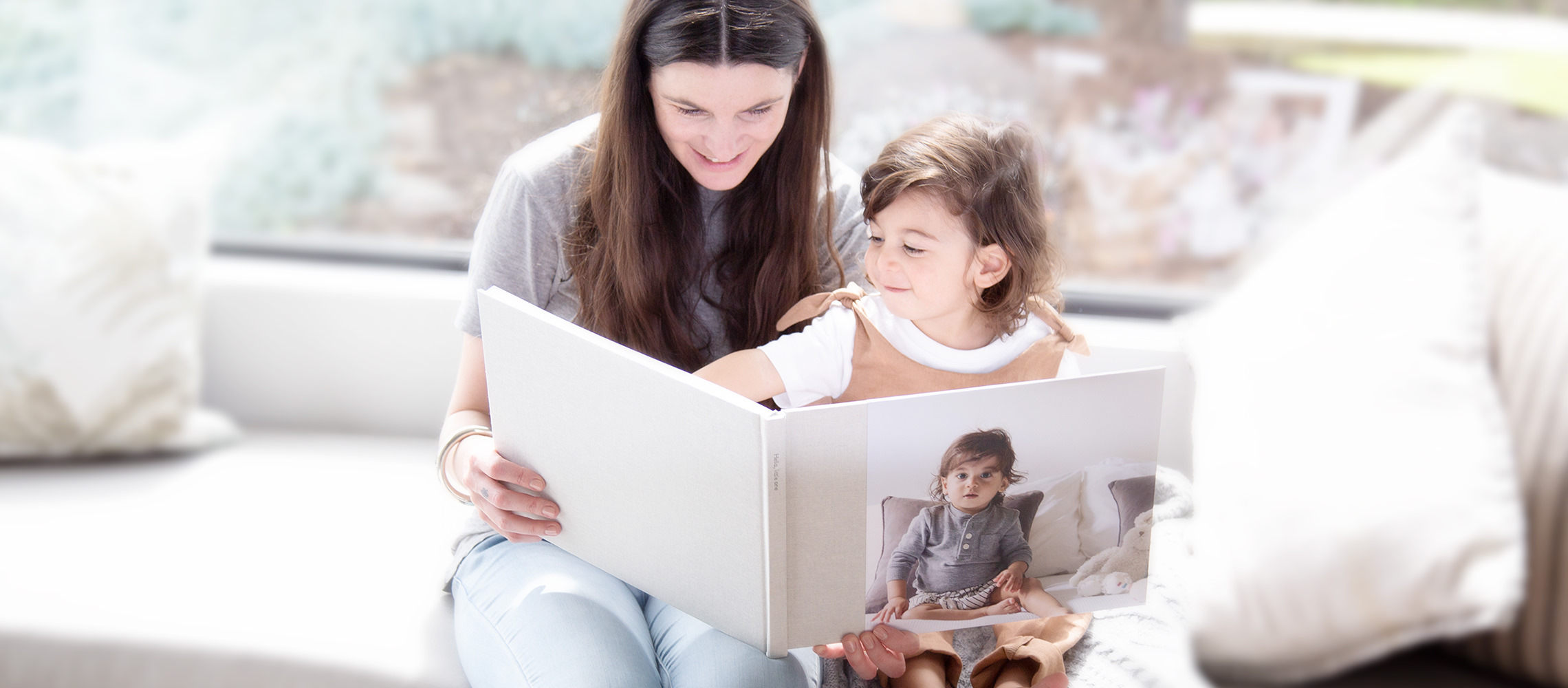 Madre che sfoglia un libro di foto con la figlia su un divano.