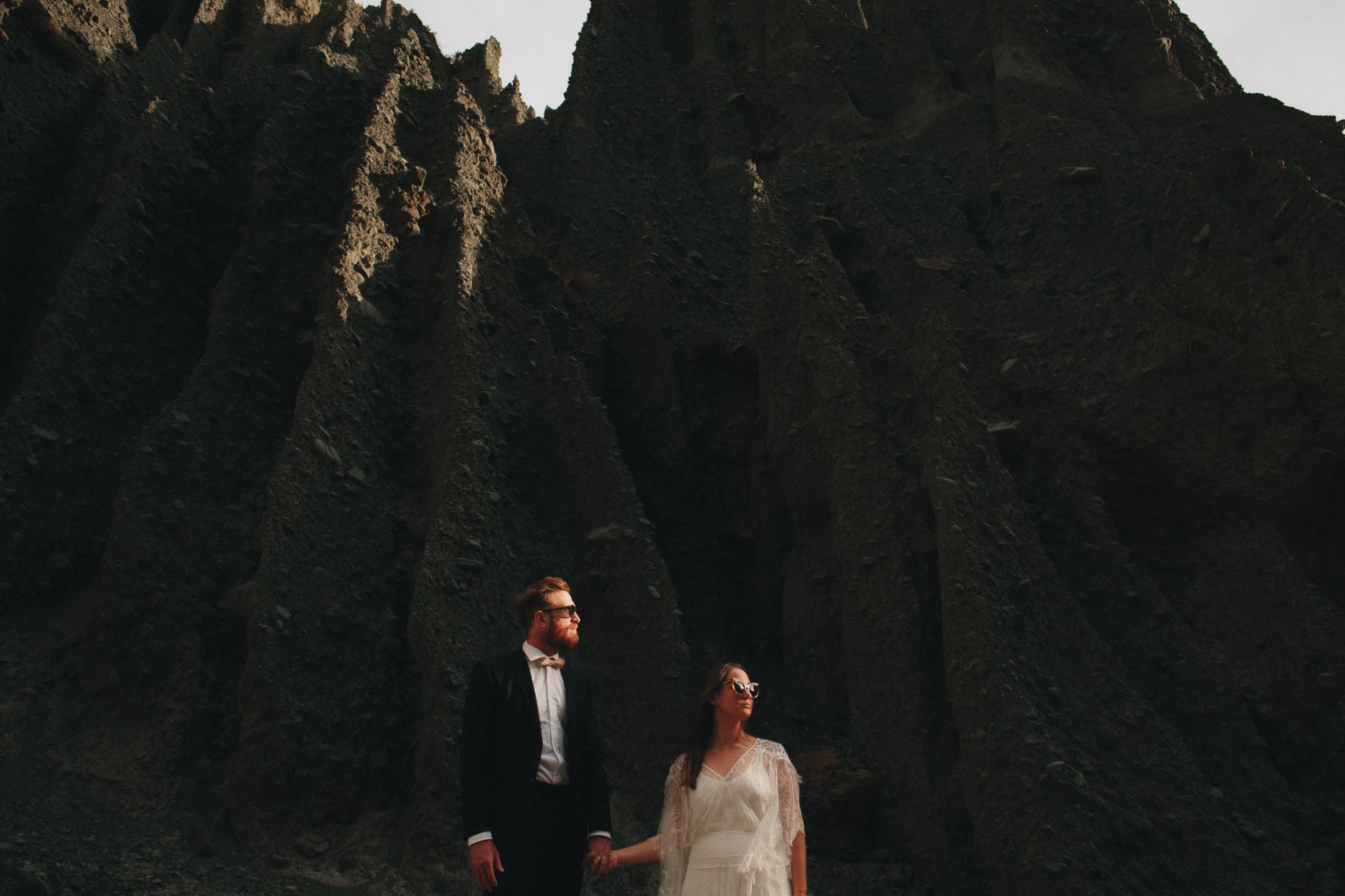 Bride and groom in sunnies posing in front of Putangirua Pinnacles