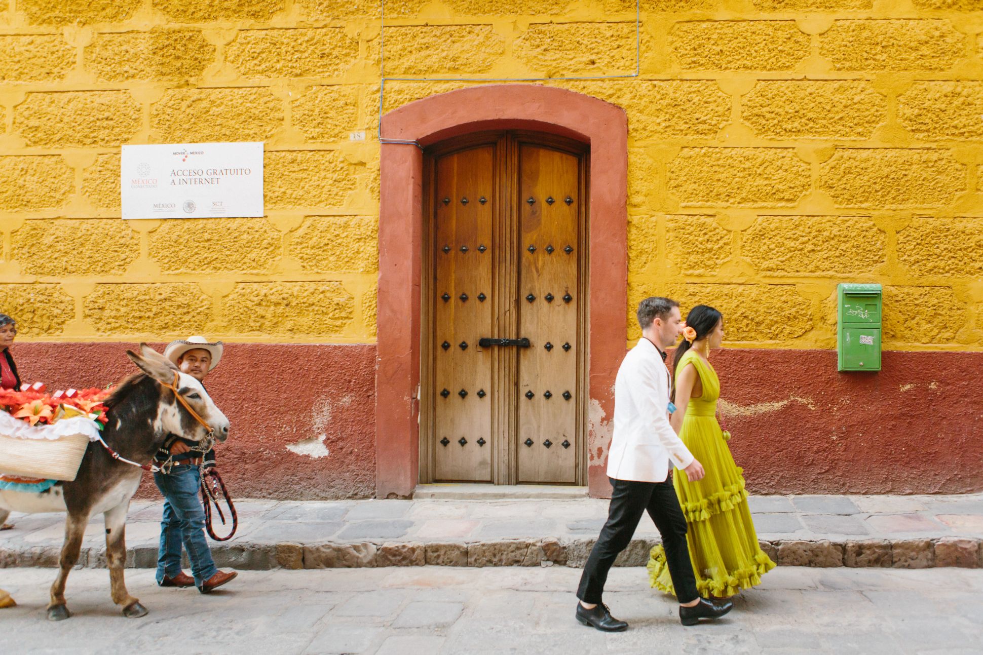 Man and woman walking down street as man and donkey follow in San Miguel de Allende