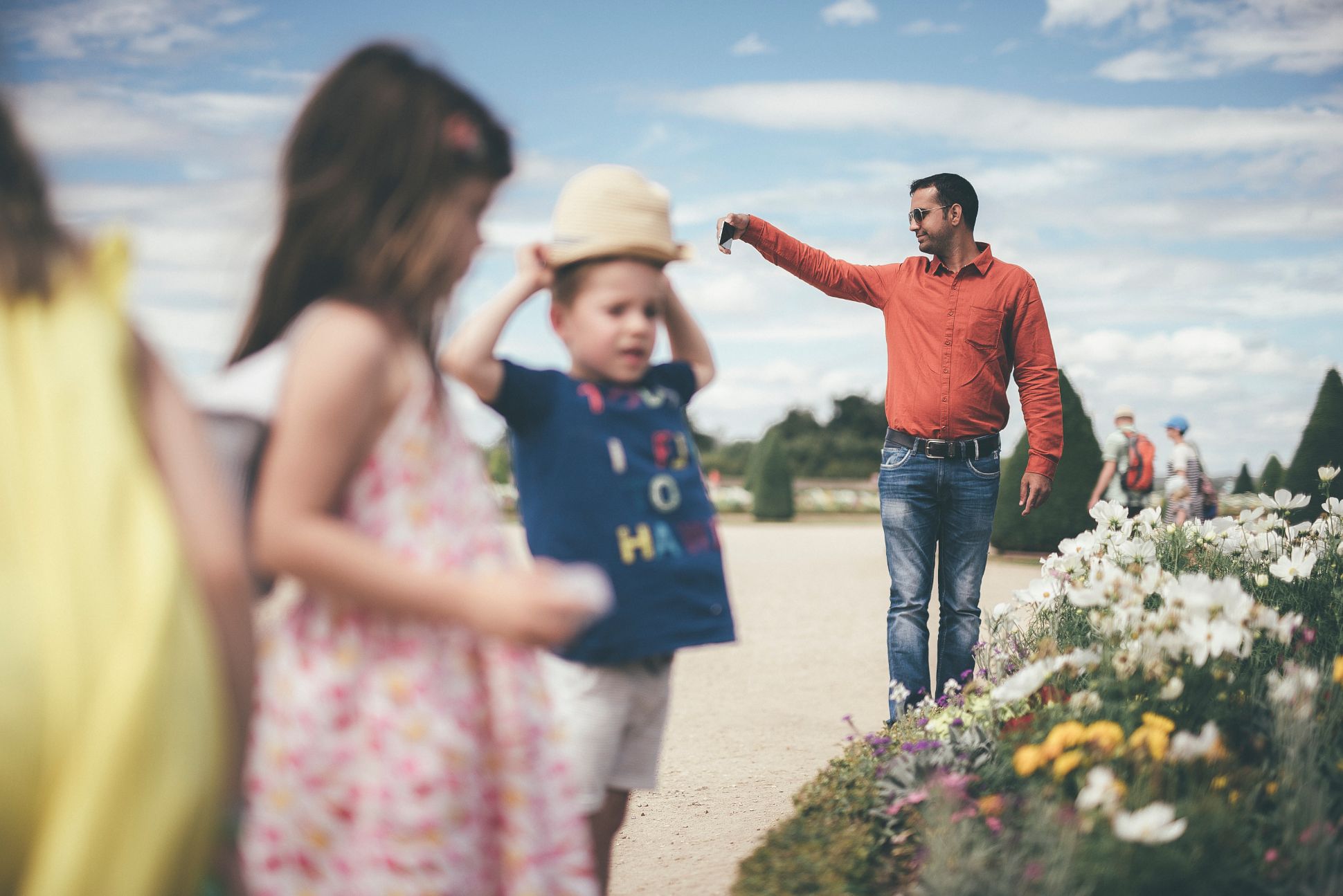 Kids playing in garden with man taking selfie in background