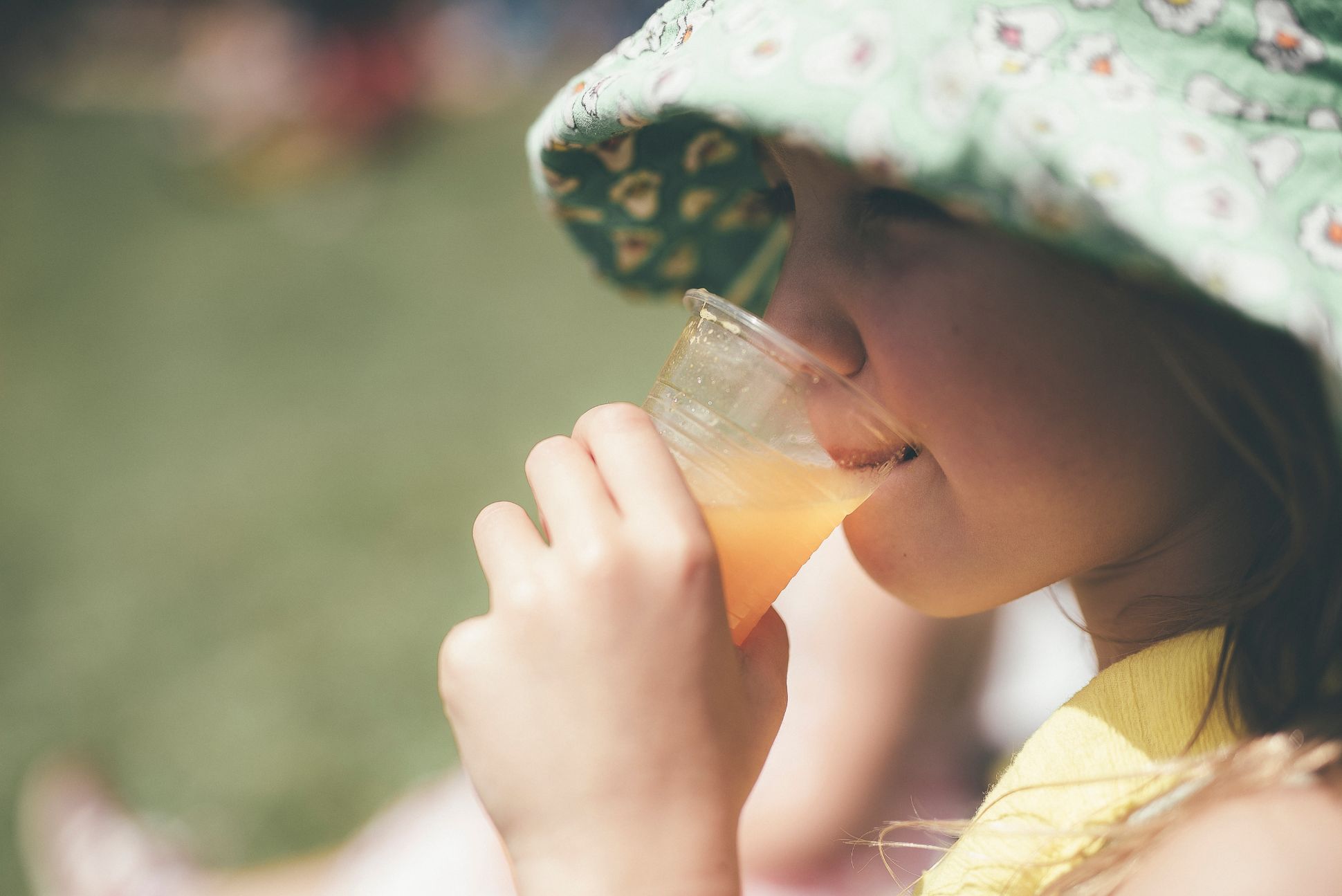 Young girl drinking orange juice from plastic cup