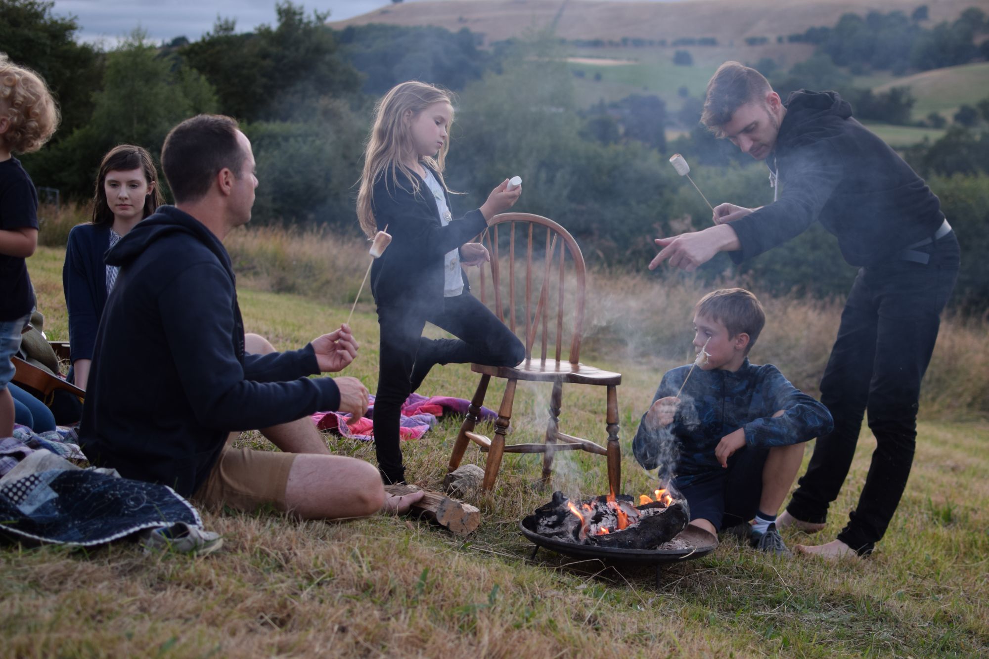 Family roasting marshmallows around fire