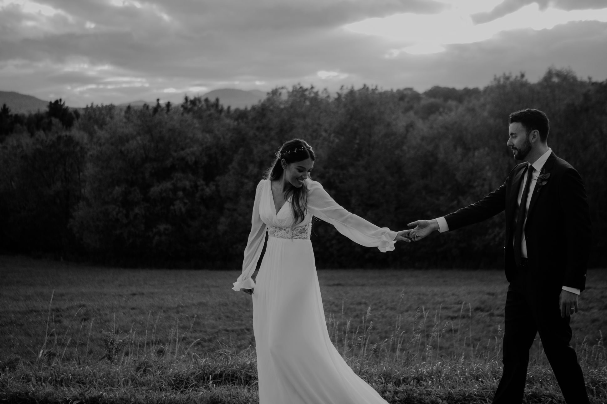 Bride and groom hand in hand in field