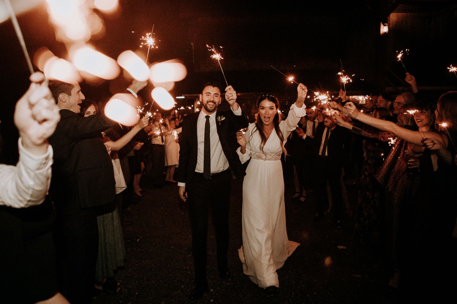 Bride, groom and guests waving sparklers