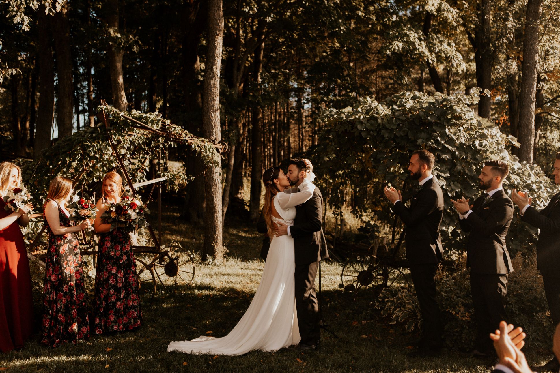Bride and groom kissing at the altar as wedding party looks on