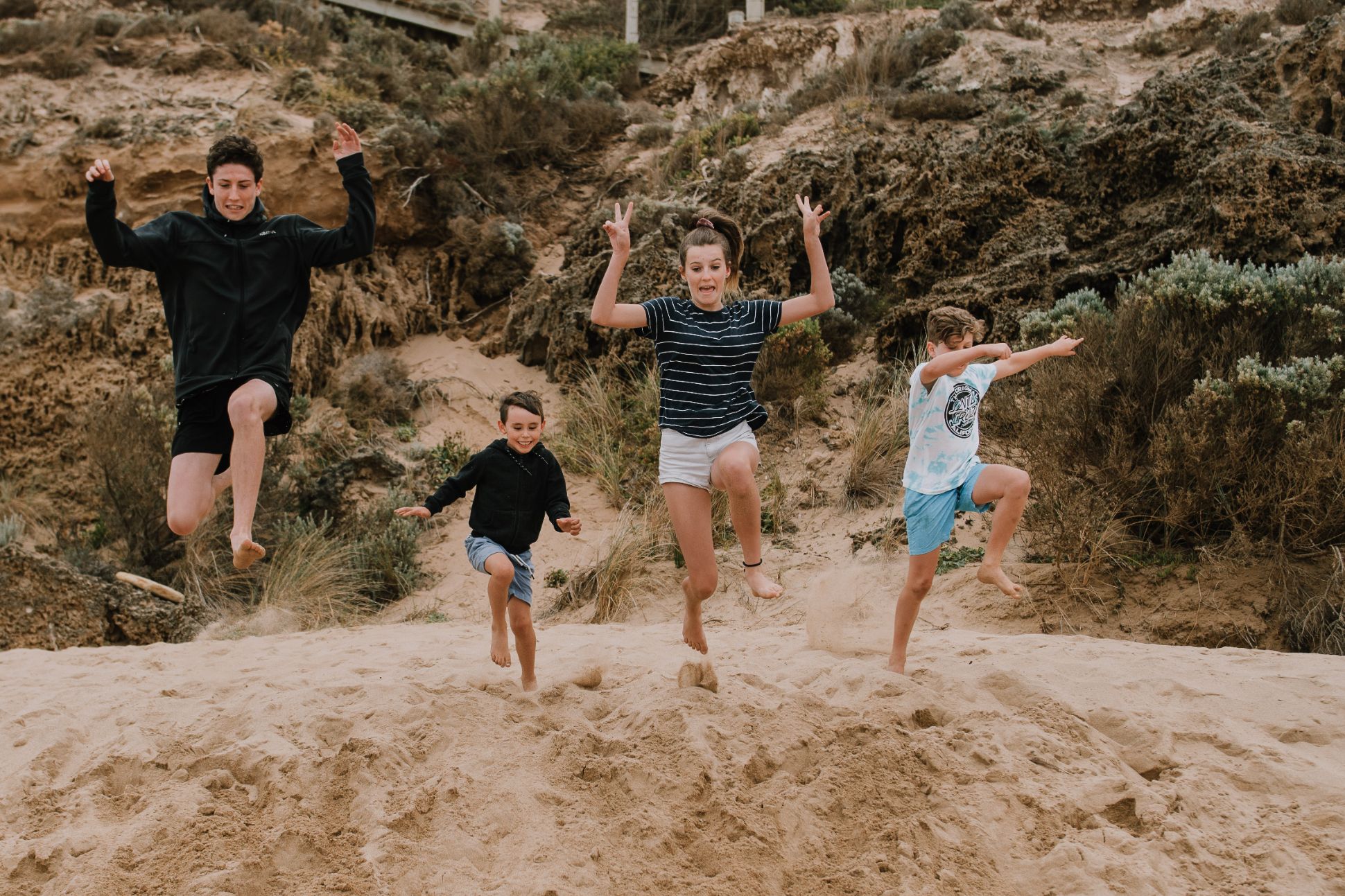 Four children jumping at the beach.