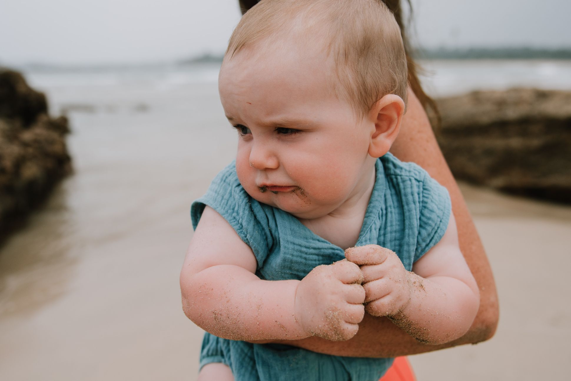 Young baby being held by a woman at the beach.