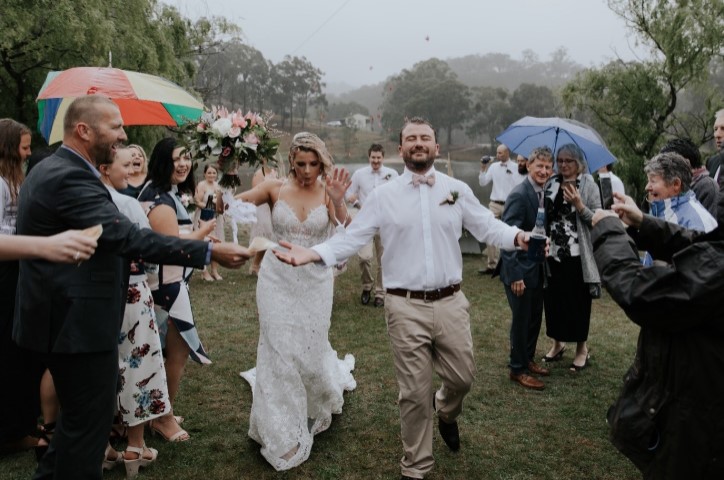 La sposa e lo sposo camminano insieme lungo la navata sotto la pioggia.