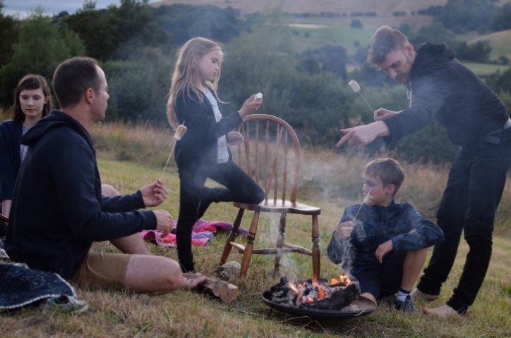 Family roasting marshmallows around fire