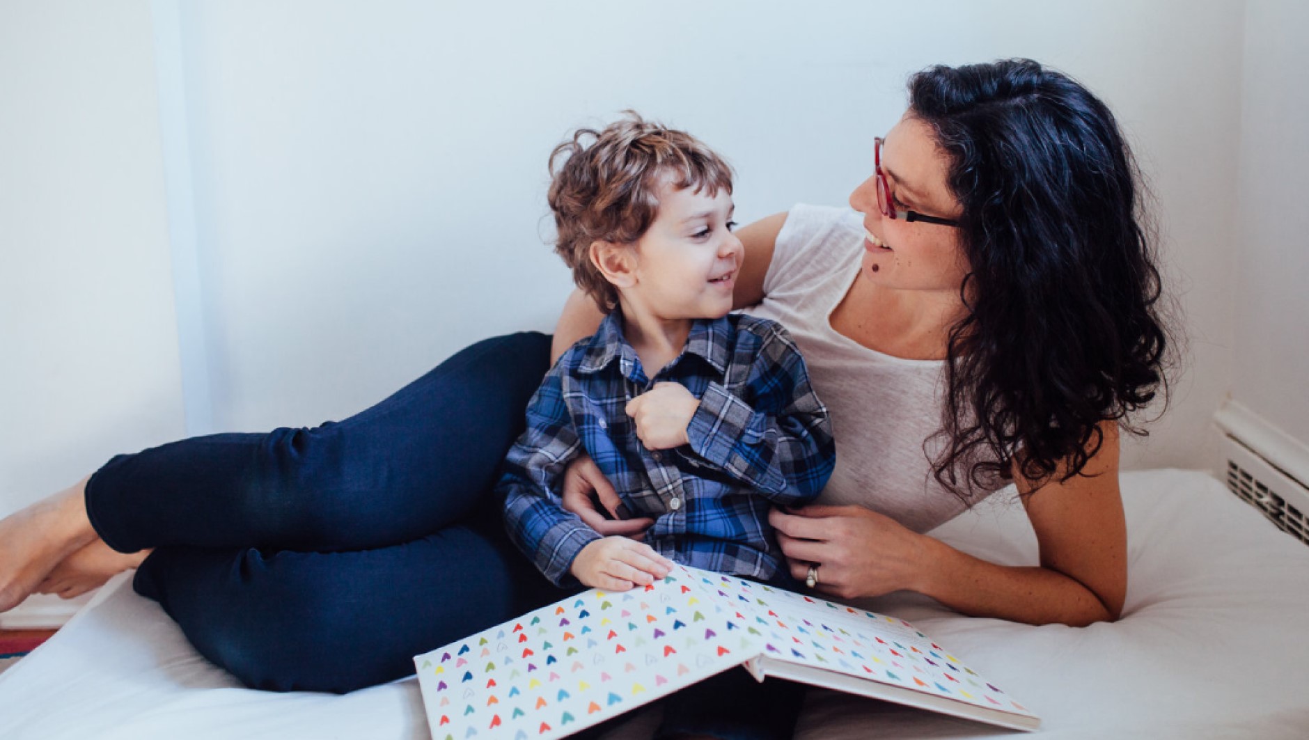 Mother and child reading a book in bed.