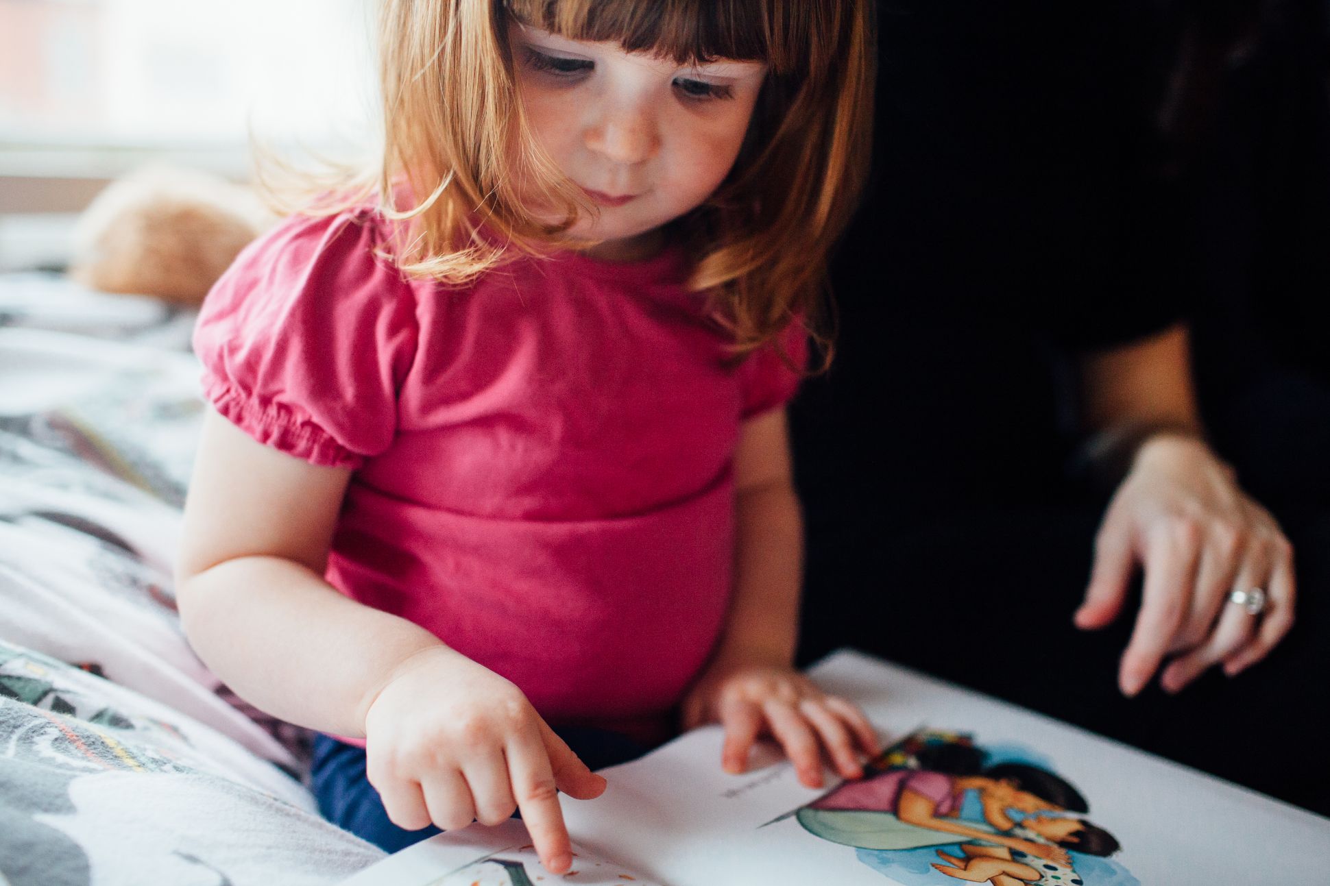 Child reading book with parent