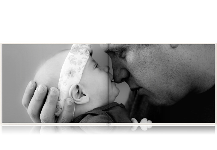 Fotolibro apaisado de bebé abierto con una foto de un padre sosteniendo a su hija.