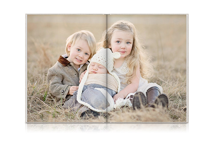 Aufgeschlagenes Familien-Fotobuch im Hochformat mit einer Darstellung von drei jungen Geschwistern auf einer Doppelseite.