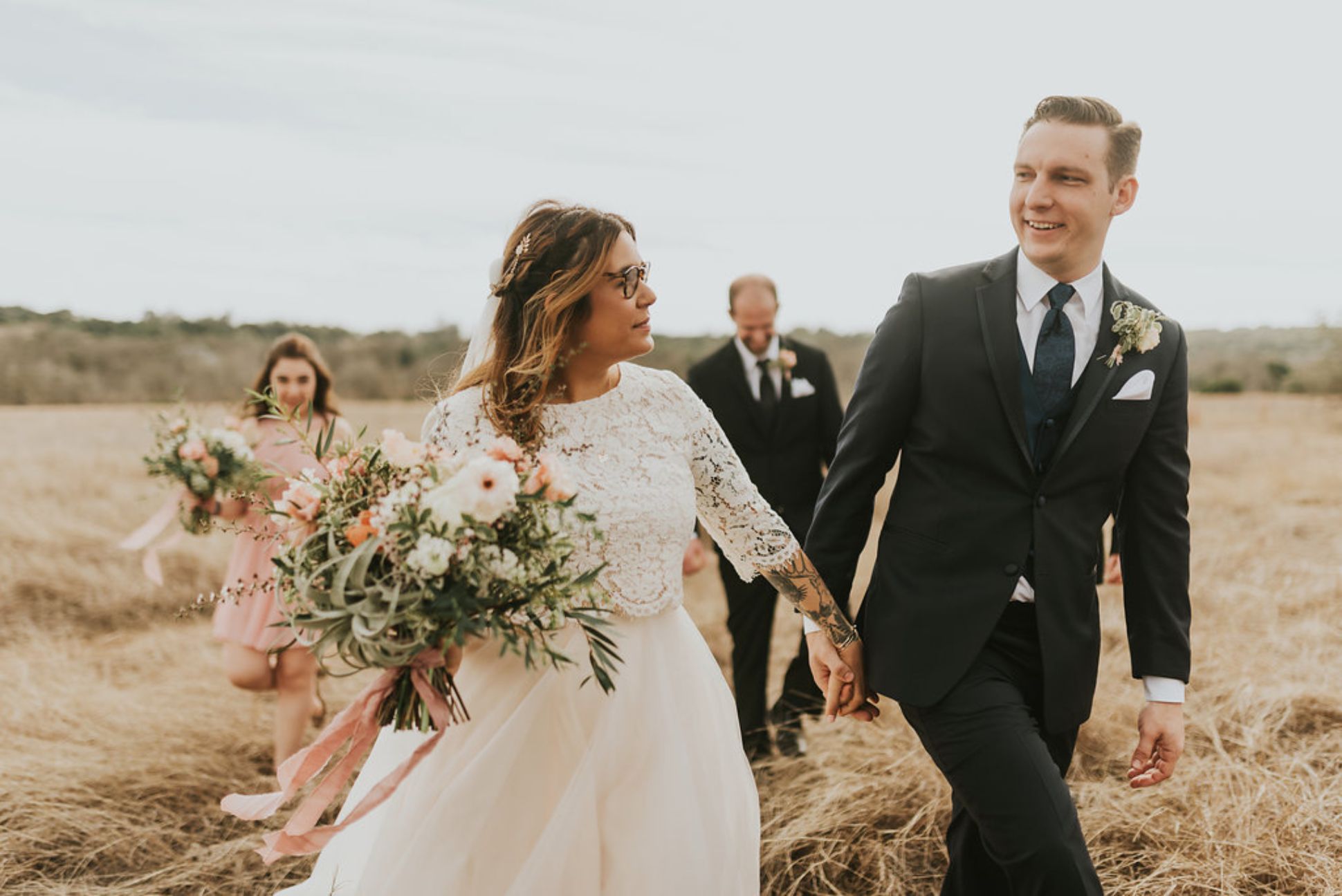 Newlyweds walking hand in hand follow by a bridesmaid and groomsman