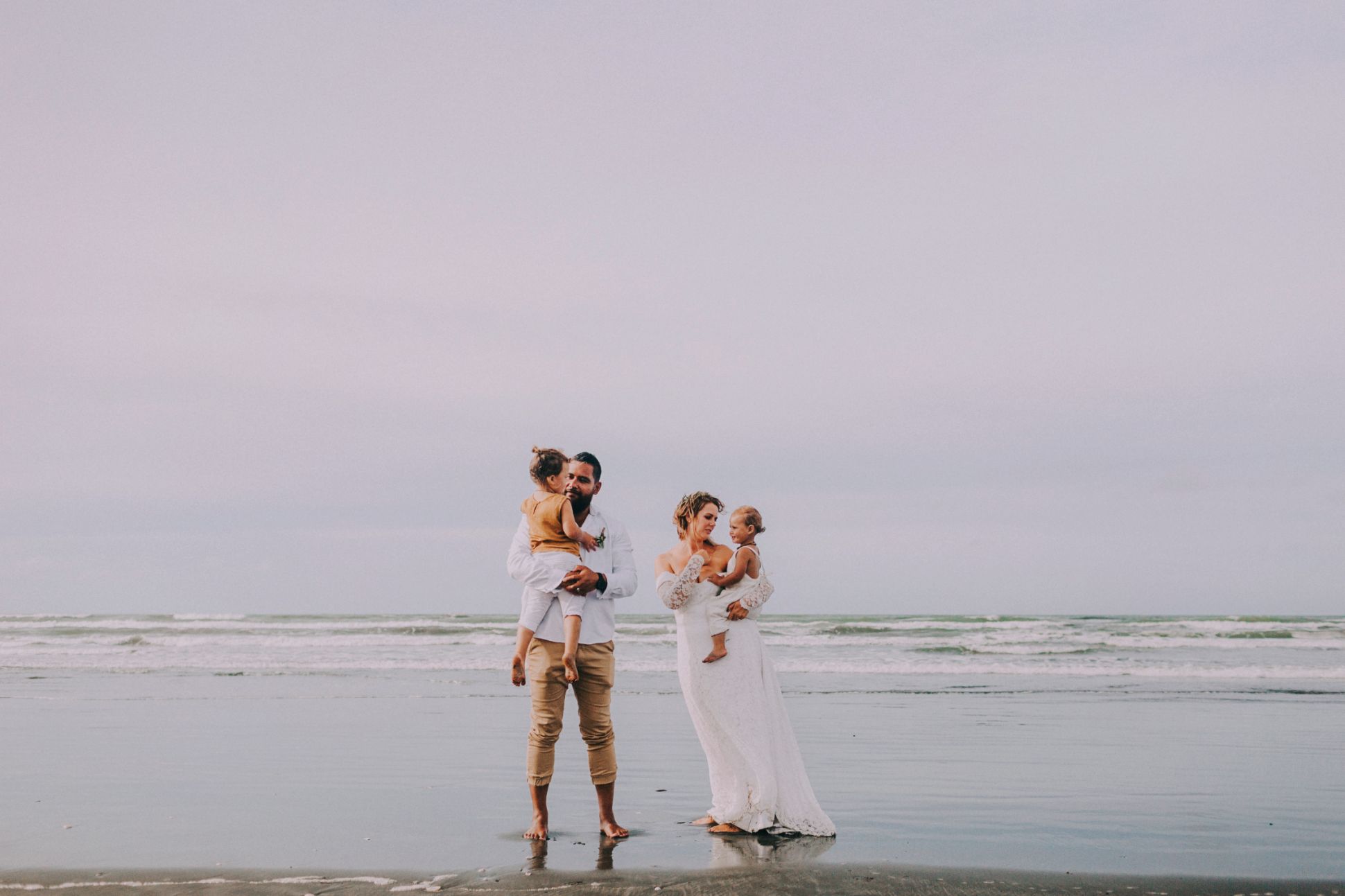 Bride and groom with their children on the beach