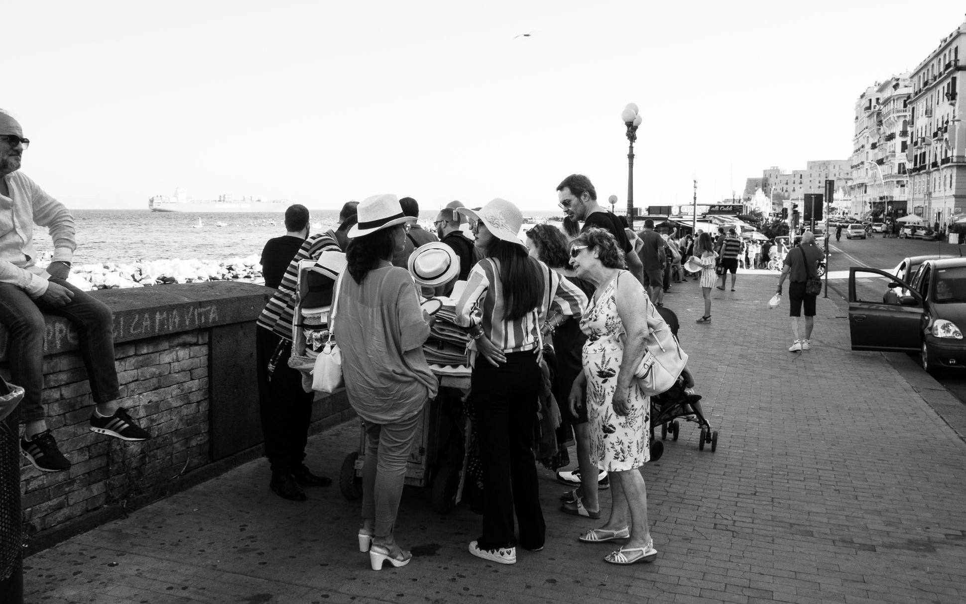 Crowd gathered in street by sea, Naples, Italy